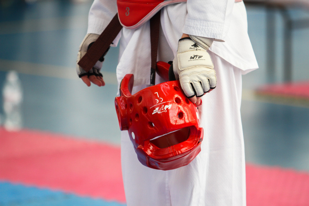 a red helmet for taekwondo, held by an athlete