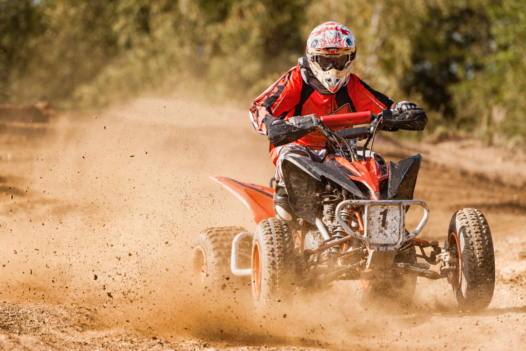 Person using an ATV on a muddy road.