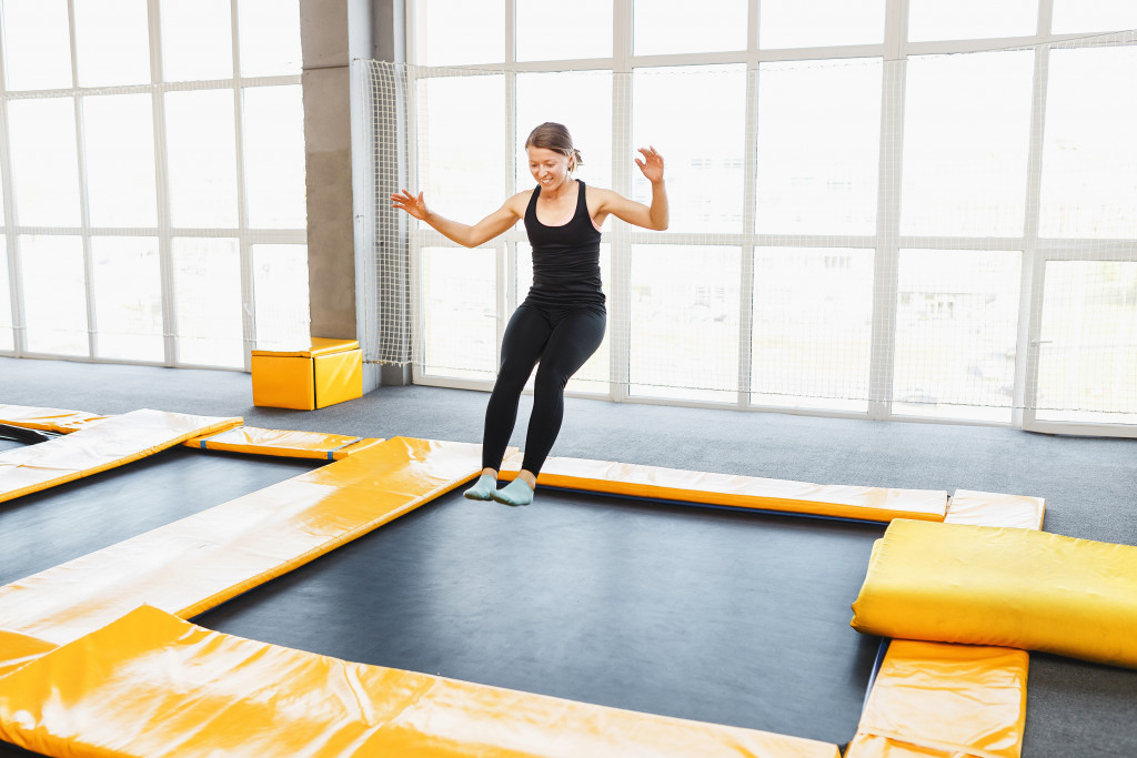 woman smiling while jumping on an indoor trampoline