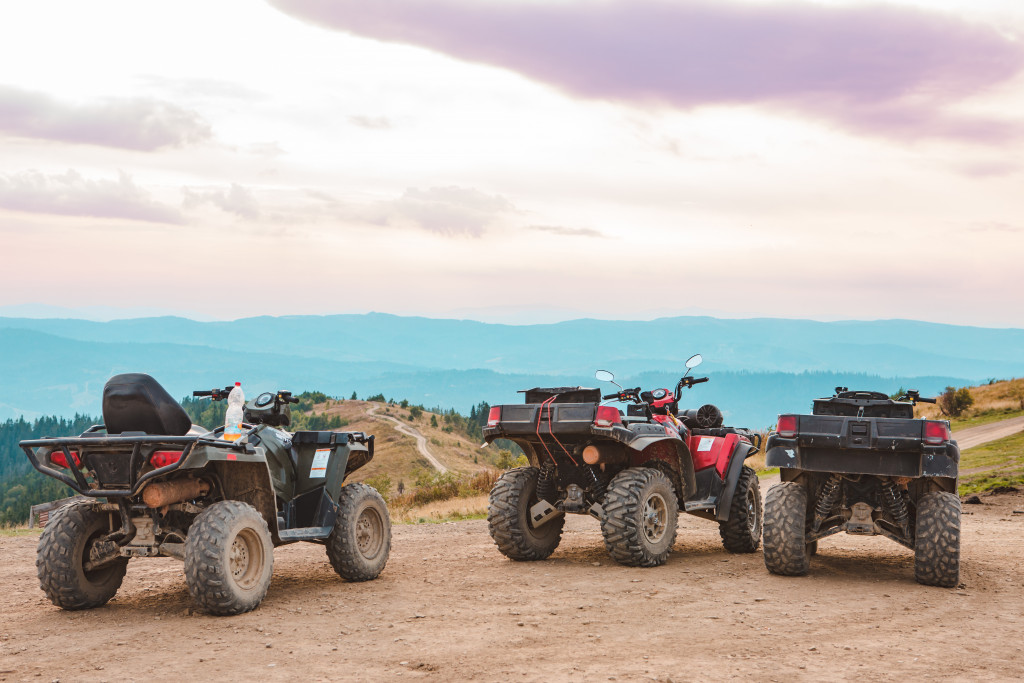 Three ATVs parked by a hill