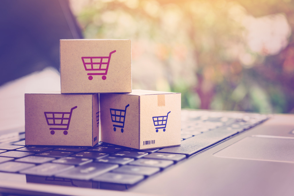 miniature boxes with shopping cart logos representing shipping and logistics on top of laptop