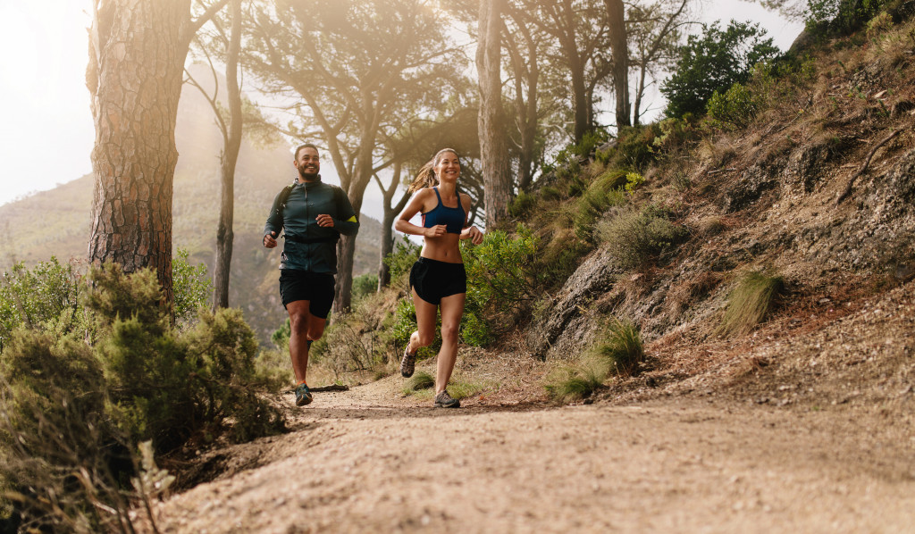 man and woman running in a mountain path in the morning