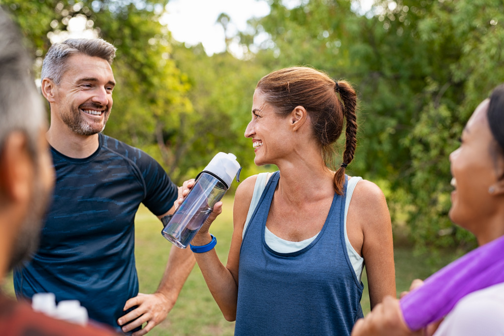 man and woman laughing with water bottle in hand after exercise