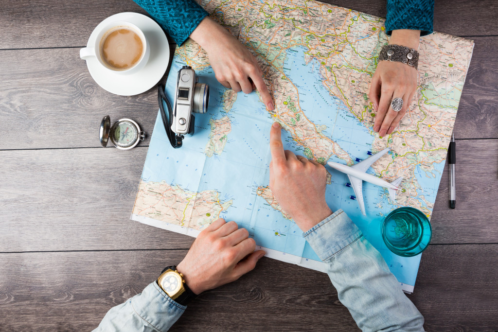 Two persons checking a map with a compass beside it.